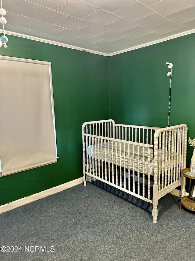 carpeted bedroom featuring a nursery area and ornamental molding