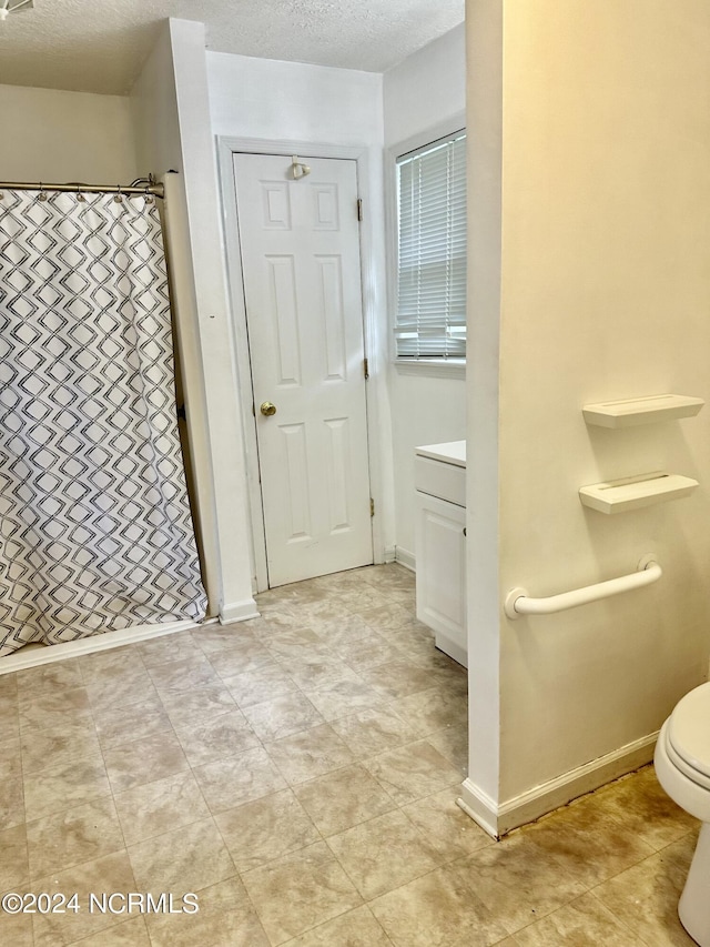 bathroom with vanity, walk in shower, a textured ceiling, and toilet