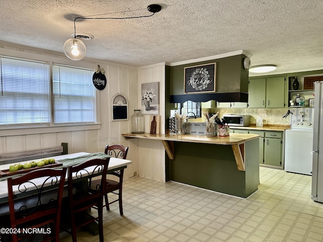 kitchen with hanging light fixtures, washer / dryer, appliances with stainless steel finishes, and green cabinets