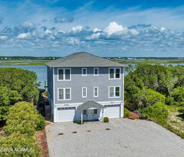 view of front of property with stairs, roof with shingles, an attached garage, and a water view