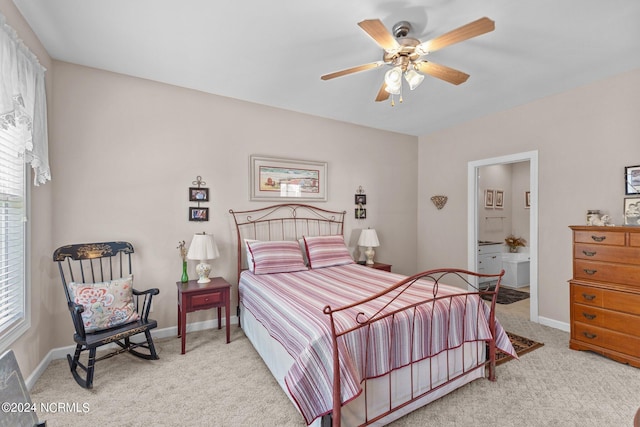 bedroom with ceiling fan, ensuite bathroom, and light colored carpet