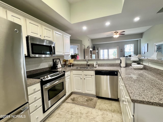 kitchen with stainless steel appliances, white cabinetry, sink, and kitchen peninsula