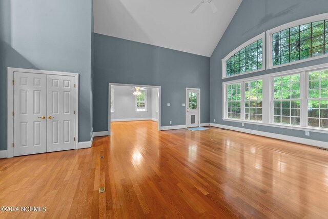 unfurnished living room featuring ceiling fan, high vaulted ceiling, and light hardwood / wood-style flooring