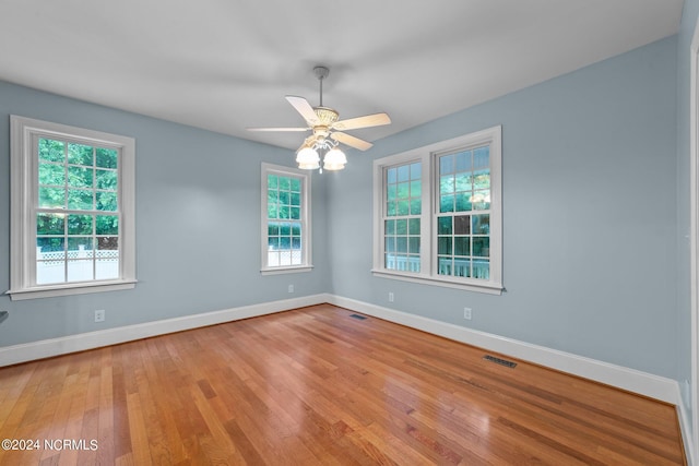 spare room with a healthy amount of sunlight, visible vents, and hardwood / wood-style floors