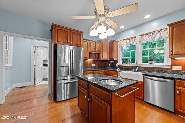 kitchen with sink, light wood-type flooring, an island with sink, ceiling fan, and stainless steel appliances