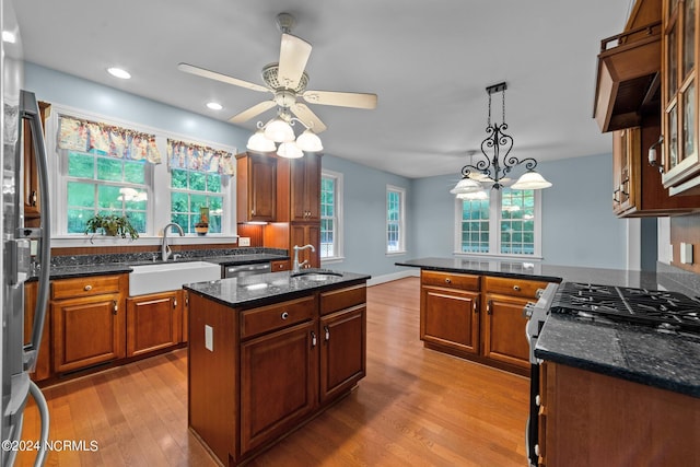 kitchen with wood finished floors, appliances with stainless steel finishes, dark stone counters, and a sink