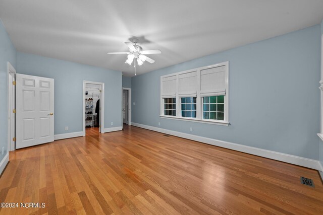 unfurnished bedroom featuring light hardwood / wood-style floors, a spacious closet, ceiling fan, and a closet