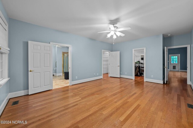 unfurnished bedroom with ceiling fan, a closet, a spacious closet, and light hardwood / wood-style floors