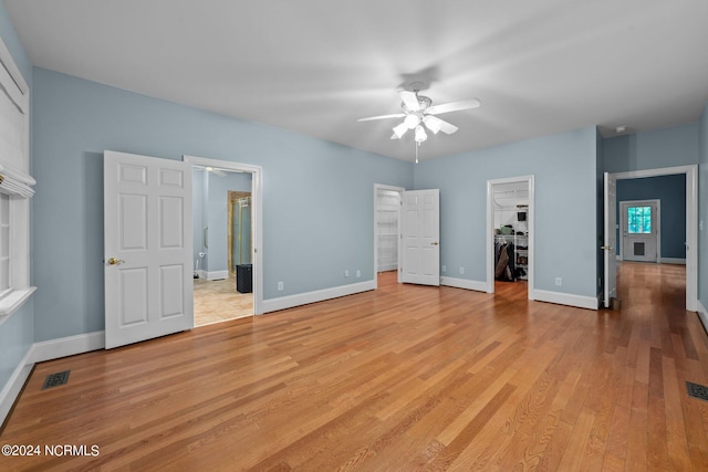 unfurnished bedroom with light wood-style floors, baseboards, a walk in closet, and a closet