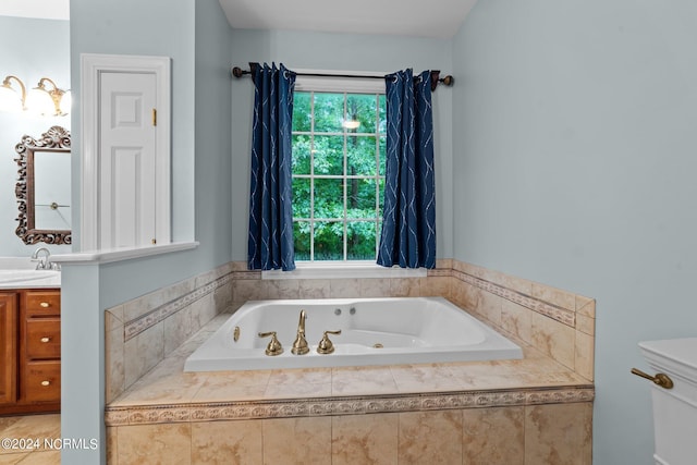 full bathroom featuring toilet, a tub with jets, and vanity