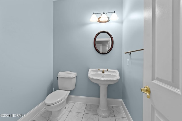 bathroom featuring marble finish floor, toilet, and baseboards