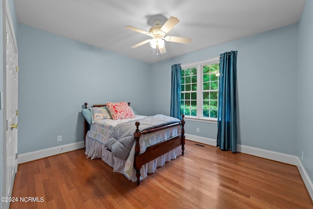 bedroom featuring visible vents, a ceiling fan, light wood-style flooring, and baseboards