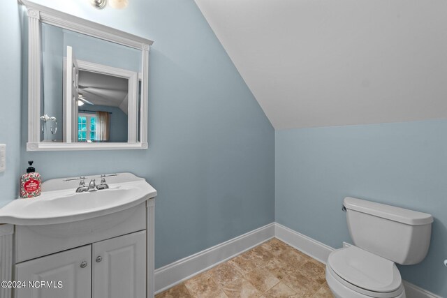 bathroom with toilet, lofted ceiling, vanity, and tile patterned floors