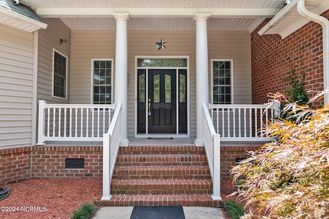 property entrance featuring a porch, crawl space, and brick siding