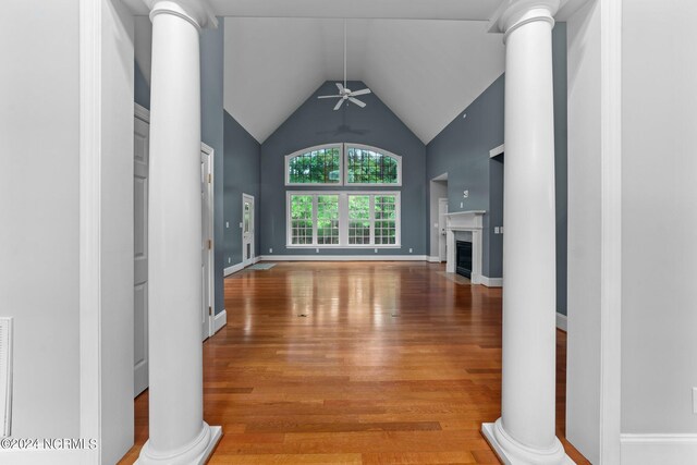 unfurnished living room with a fireplace with flush hearth, vaulted ceiling, ornate columns, and wood finished floors