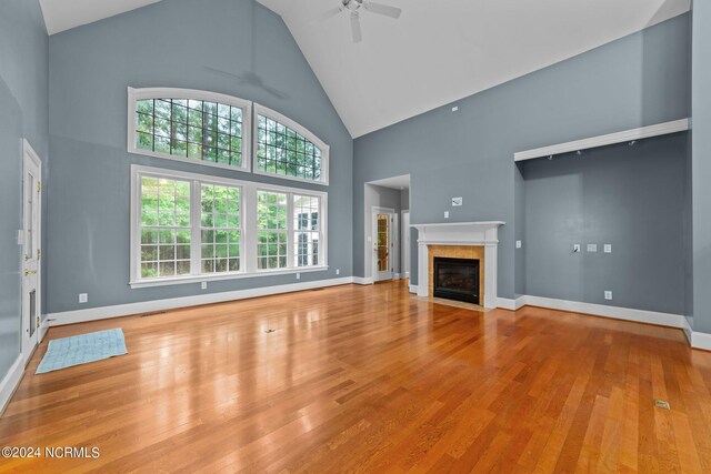 unfurnished living room with ceiling fan, high vaulted ceiling, light hardwood / wood-style flooring, and a fireplace