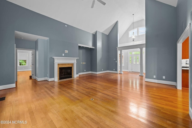 unfurnished living room featuring high vaulted ceiling, hardwood / wood-style floors, a fireplace with flush hearth, and visible vents