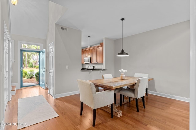 dining room with high vaulted ceiling and light wood-type flooring