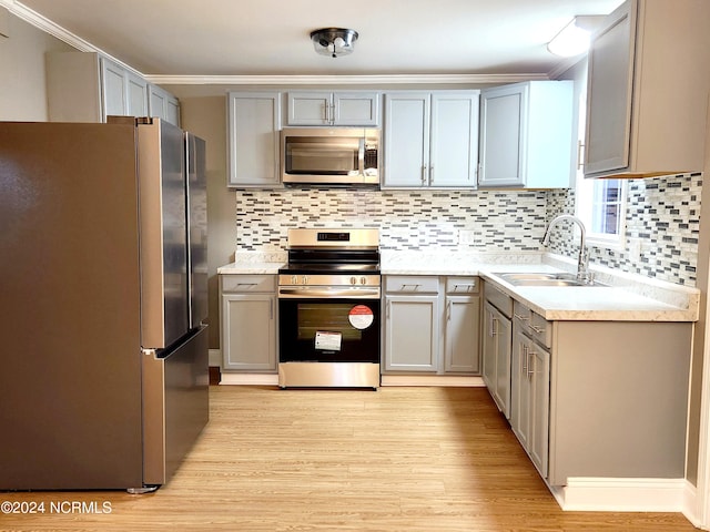 kitchen featuring appliances with stainless steel finishes, gray cabinets, sink, tasteful backsplash, and light hardwood / wood-style flooring