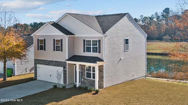 view of front of property with a front yard, a water view, and a garage