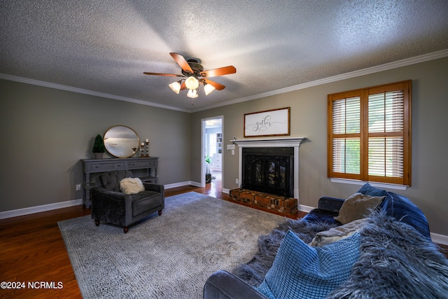 living room featuring a textured ceiling, a fireplace, hardwood / wood-style floors, crown molding, and ceiling fan