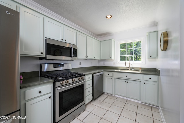 kitchen featuring a textured ceiling, stainless steel appliances, sink, light tile patterned flooring, and ornamental molding