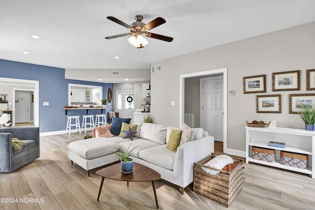 living area with light wood-style floors, baseboards, visible vents, and ceiling fan