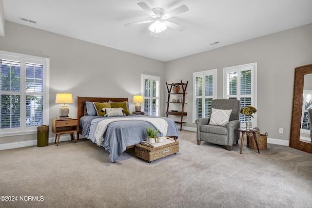 carpeted bedroom featuring a ceiling fan, visible vents, and baseboards