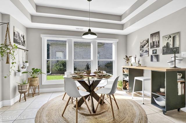 dining area with a raised ceiling, visible vents, baseboards, and light tile patterned floors