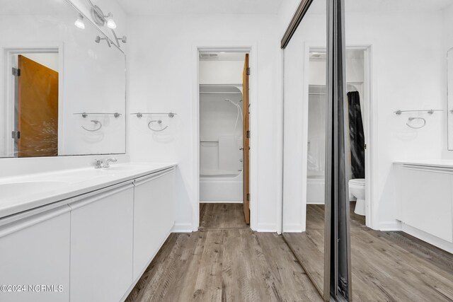 full bathroom with shower / tub combination, dual vanity, toilet, and hardwood / wood-style flooring