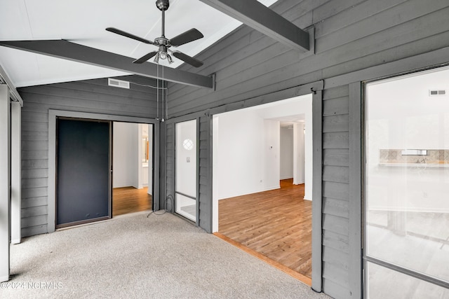 carpeted empty room with ceiling fan and lofted ceiling with beams