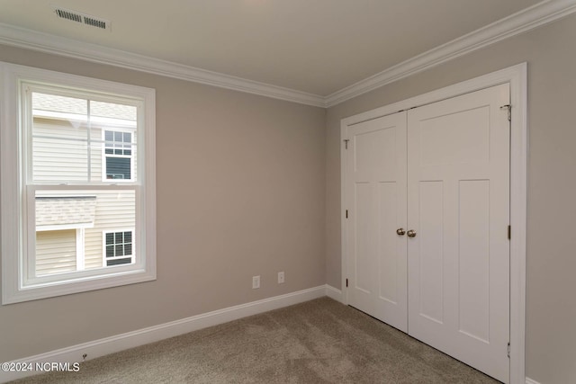 unfurnished bedroom with ornamental molding, a closet, and carpet