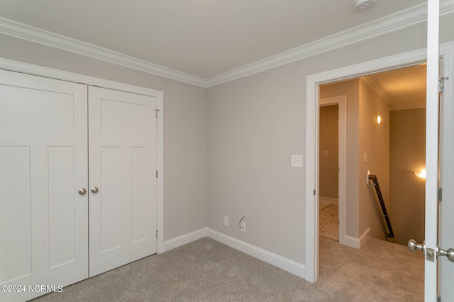 unfurnished bedroom featuring crown molding, light colored carpet, and a closet