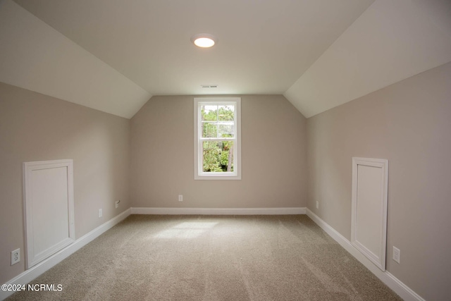 additional living space featuring lofted ceiling and light carpet