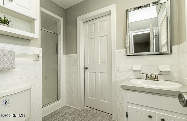 bathroom with toilet, a shower with shower door, and tile walls