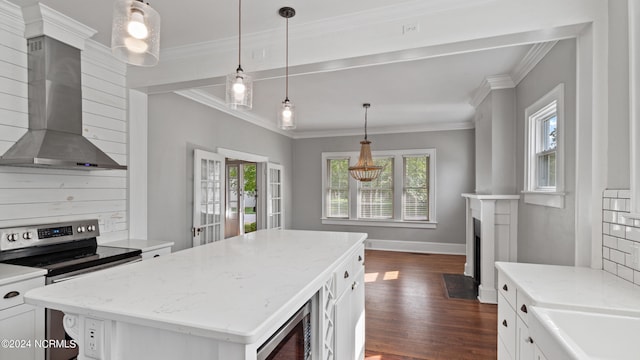 kitchen featuring white cabinetry, appliances with stainless steel finishes, a center island, wall chimney range hood, and dark hardwood / wood-style flooring