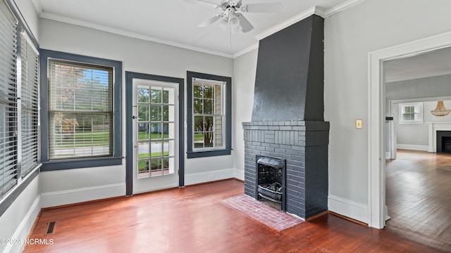 unfurnished living room featuring plenty of natural light, crown molding, dark hardwood / wood-style floors, and a brick fireplace