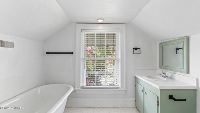 bathroom with vanity, a tub to relax in, and vaulted ceiling