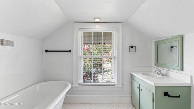 bathroom with baseboards, visible vents, vaulted ceiling, vanity, and a freestanding tub