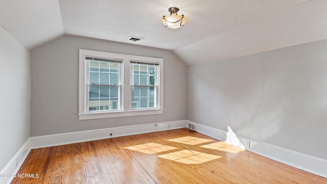 additional living space with visible vents, baseboards, vaulted ceiling, and wood finished floors