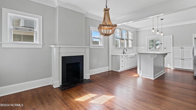 unfurnished living room with dark wood-style floors, a fireplace with flush hearth, ornamental molding, and baseboards