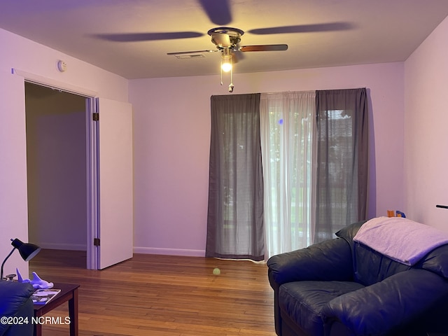 interior space featuring a ceiling fan, baseboards, and wood finished floors