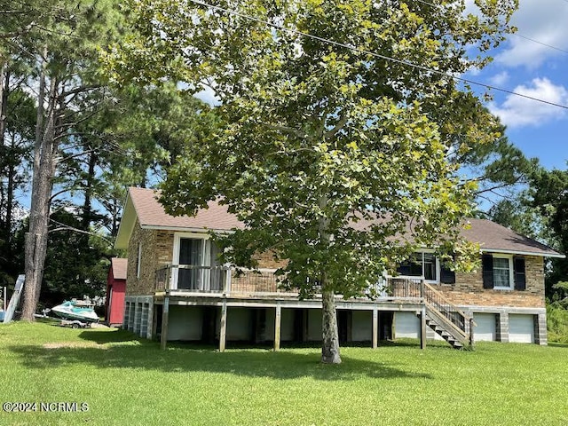 rear view of house with brick siding, stairway, an attached garage, and a lawn