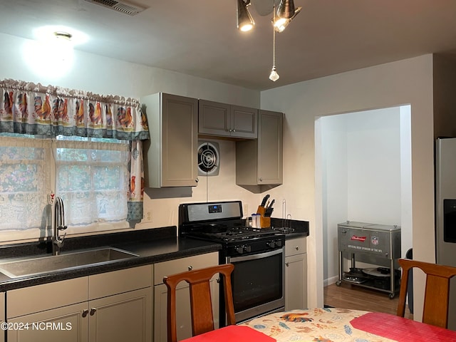 kitchen featuring stainless steel gas range, gray cabinetry, sink, and hardwood / wood-style flooring