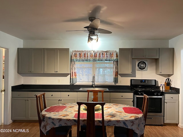 kitchen with stainless steel gas range oven, sink, gray cabinetry, and light wood-type flooring