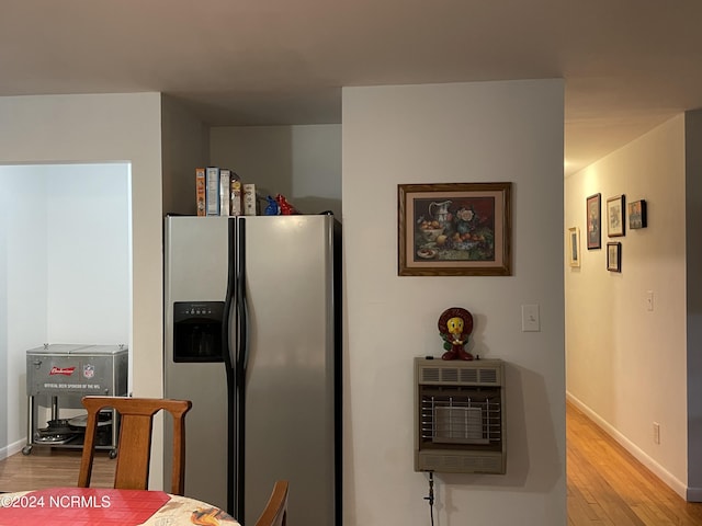 kitchen with baseboards, stainless steel refrigerator with ice dispenser, light wood-style flooring, and heating unit