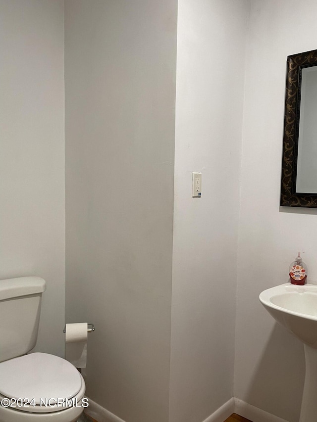 half bathroom with baseboards and toilet