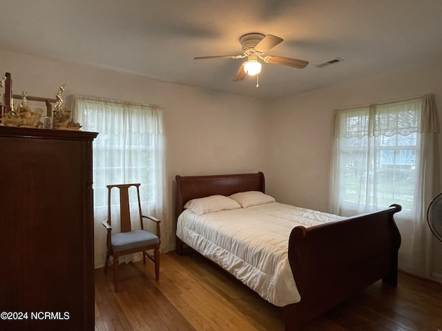 bedroom with a ceiling fan, visible vents, and wood finished floors