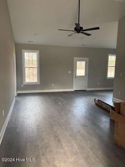 unfurnished living room with dark hardwood / wood-style floors, a wealth of natural light, and ceiling fan