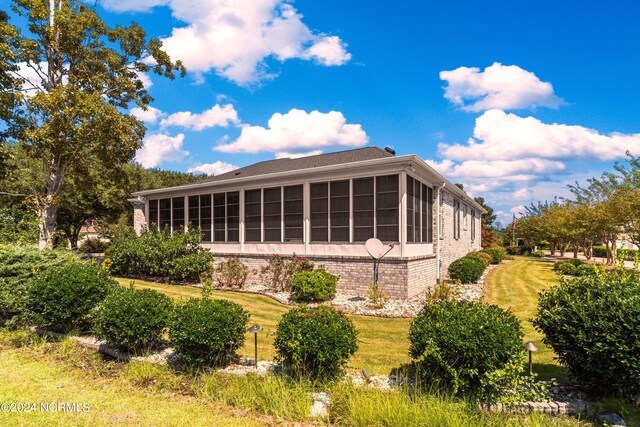 rear view of property featuring a yard and a sunroom